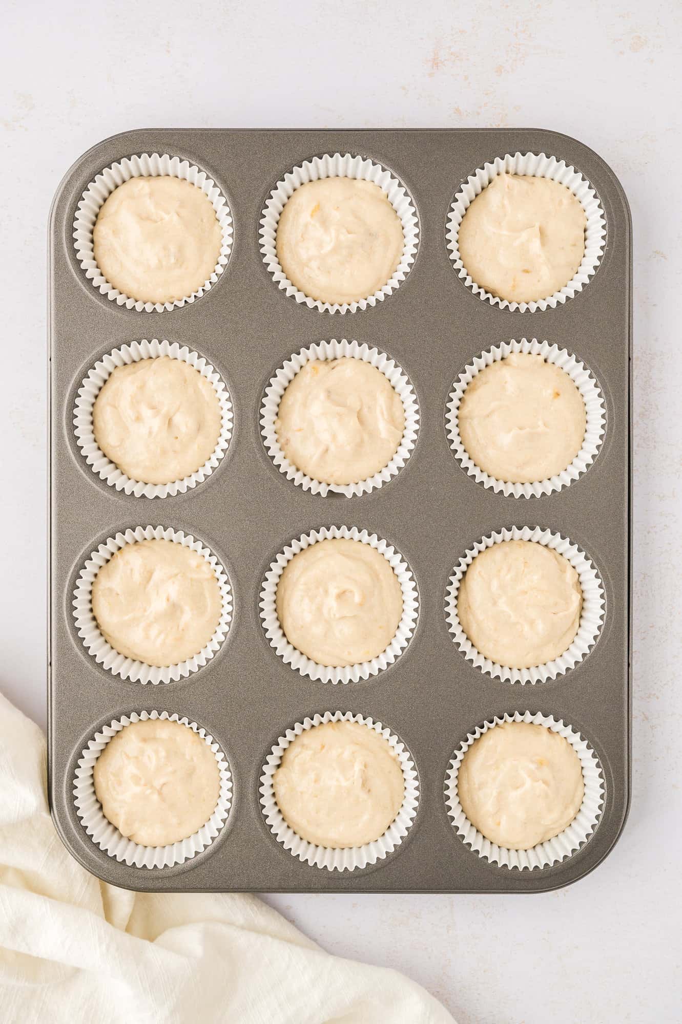 Cupcake batter added to paper lined muffin tin.