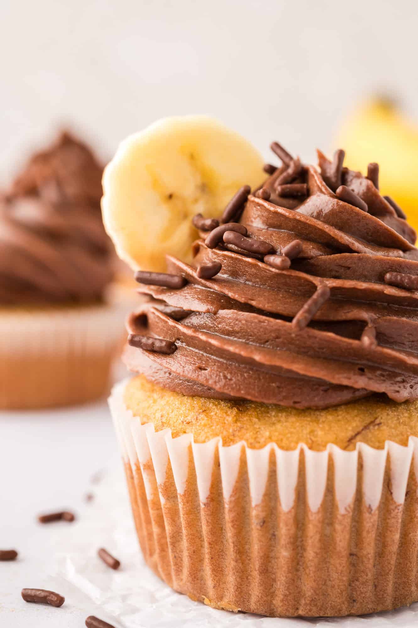 Banana cupcake topped with chocolate frosting and a slice of banana.