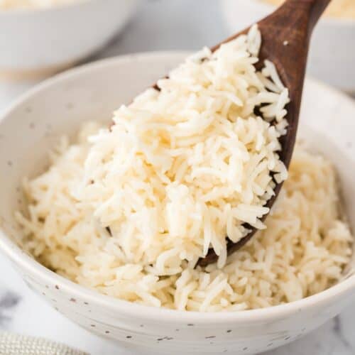 Instant pot basmati rice on a wooden spoon and in a white bowl.