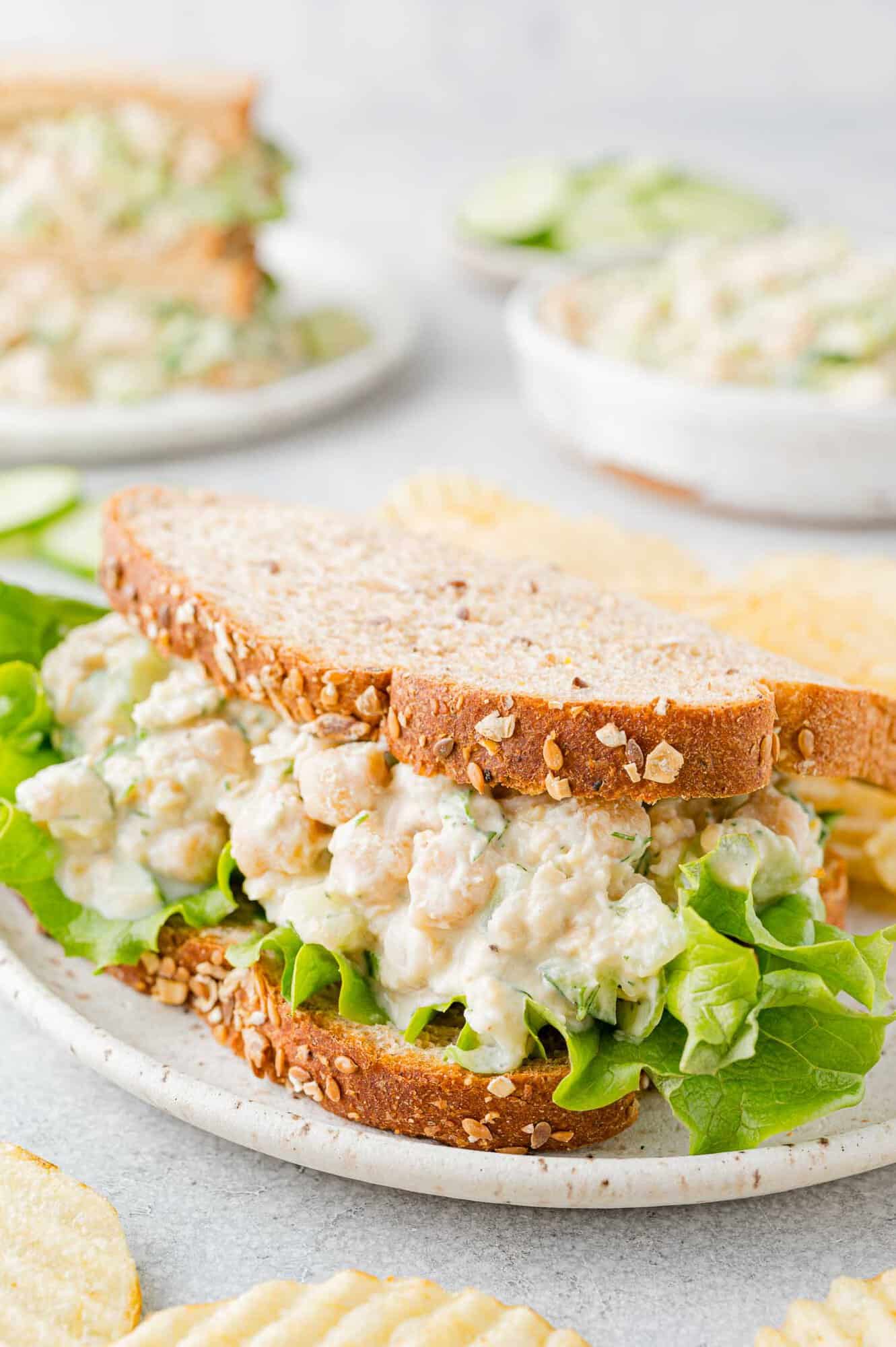 Chickpea salad sandwich on wheat bread with leaf lettuce.