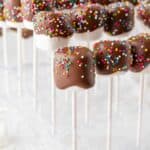 Chocolate covered marshmallows on sticks, with sprinkles.