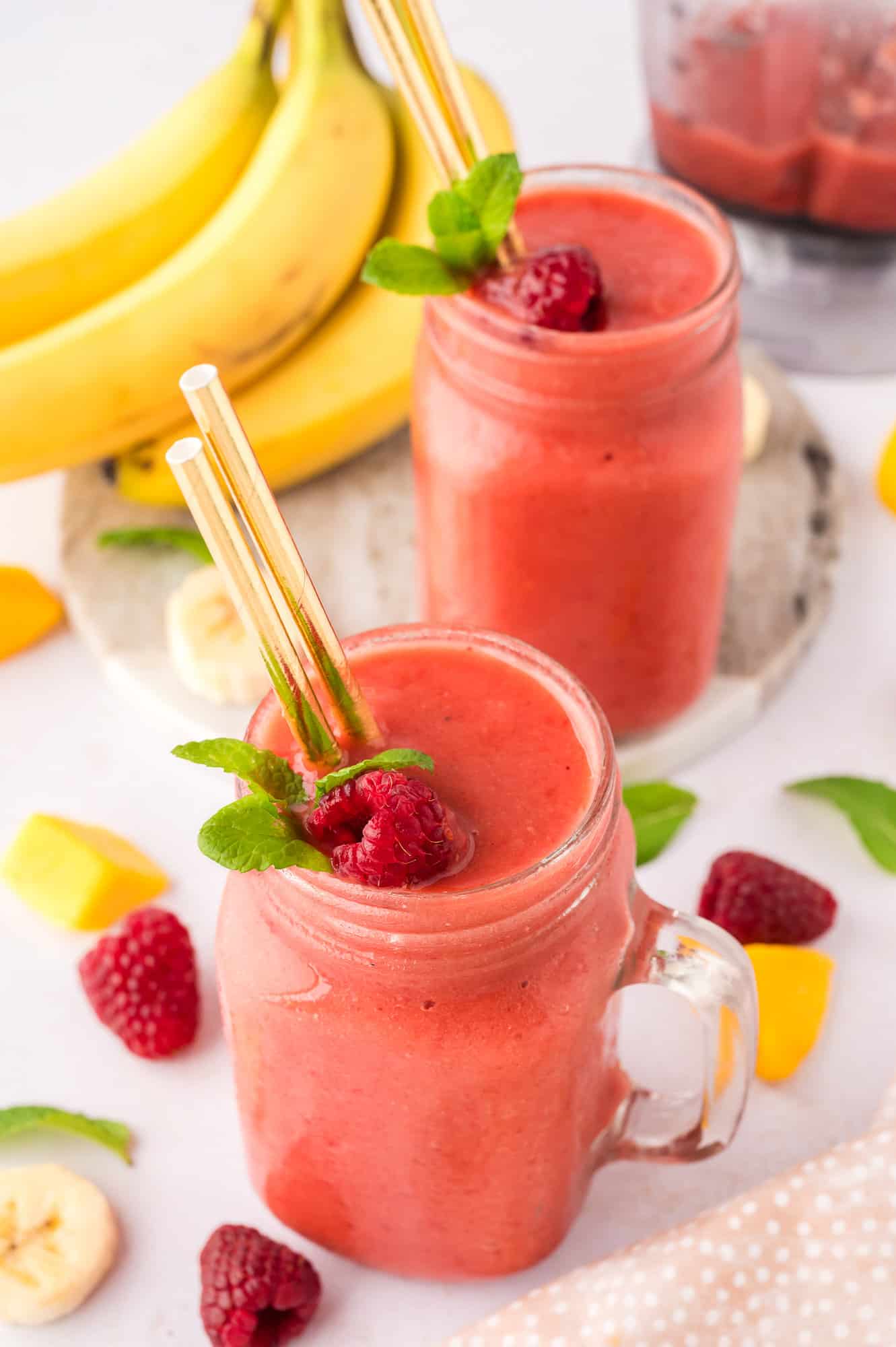 Two coconut water smoothies, with individual ingredients scattered around.