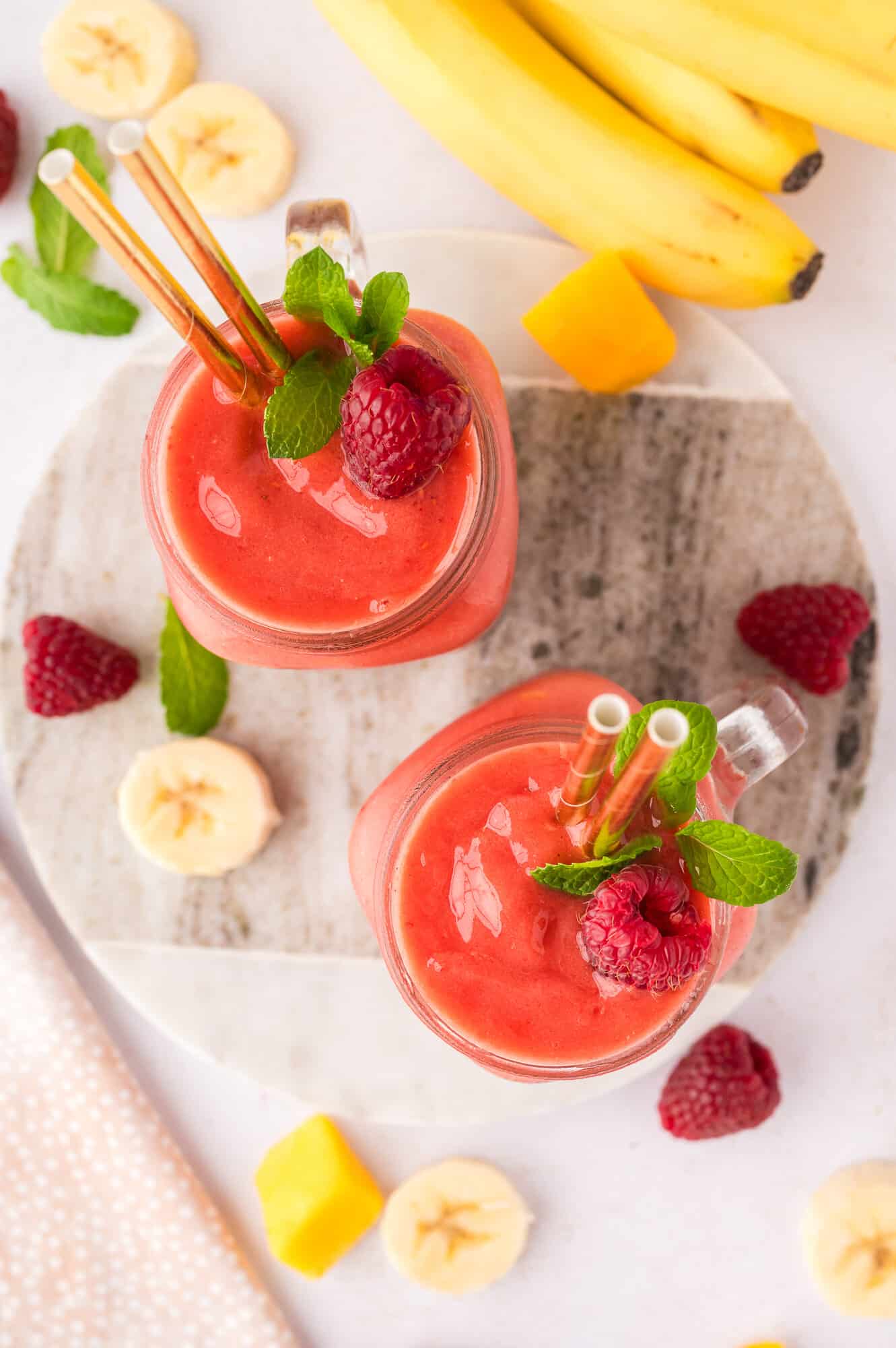 Overhead view of two coconut water smoothies with raspberries.