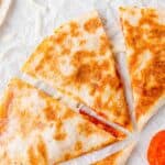 Overhead view of pizza quesadilla, cut into wedges.
