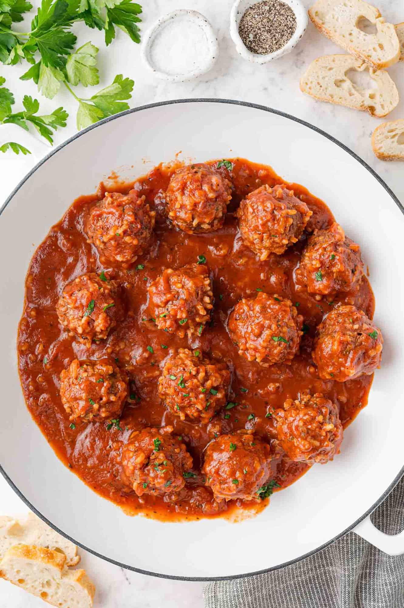 Cooked meatballs in pan, surrounded by ingredients used in them.