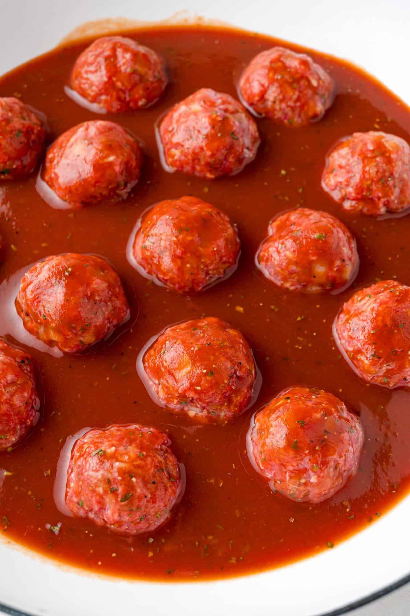 Tomato sauce and uncooked meatballs.