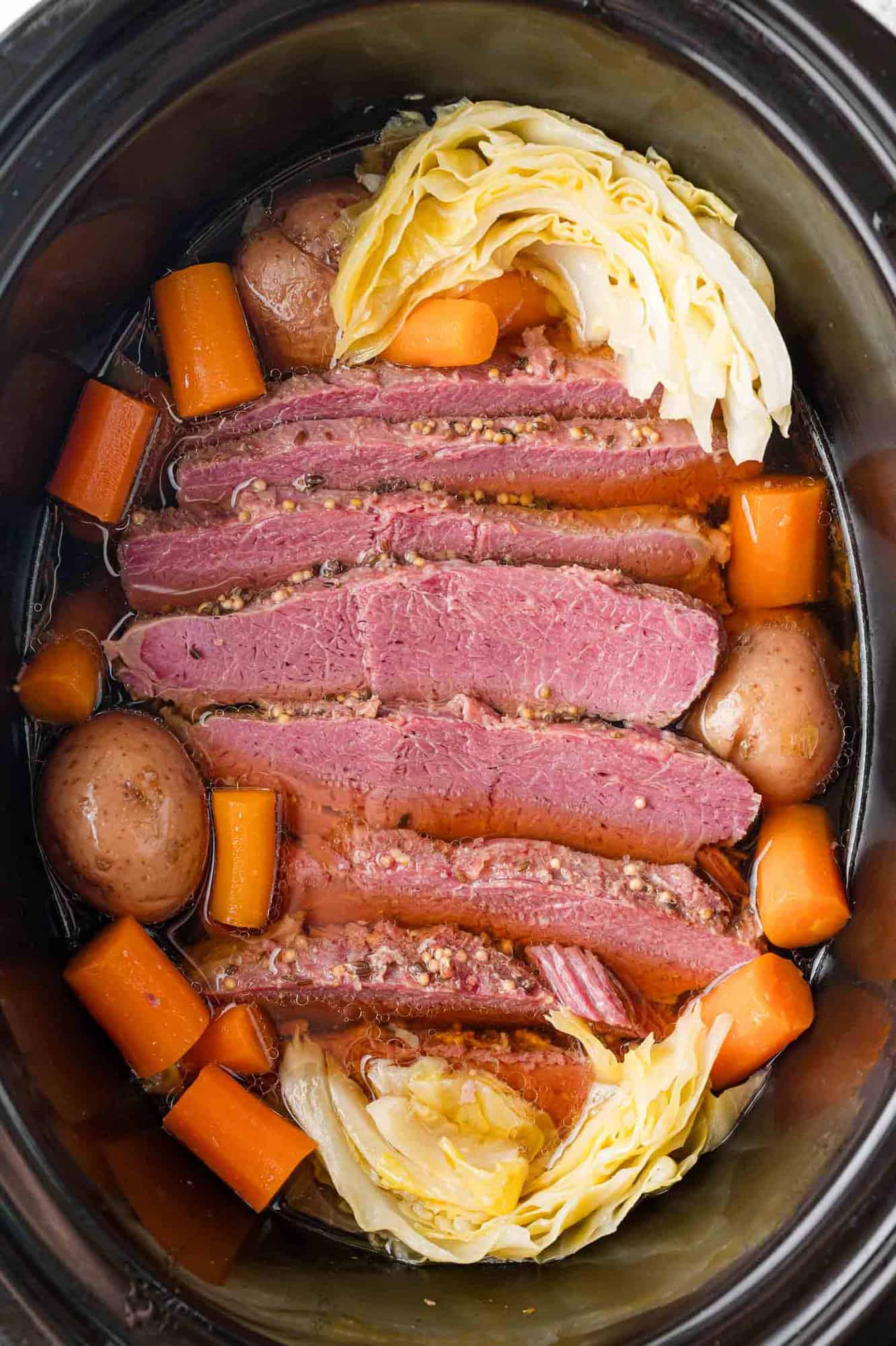 Corned beef in a crockpot with cabbage, potatoes, carrots.