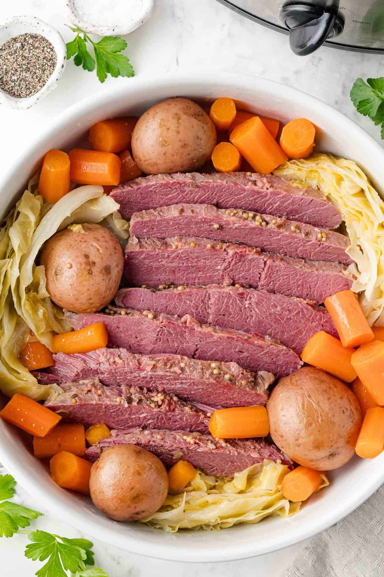 Corned beef brisket arranged on a platter with potatoes, carrots, and cabbage.