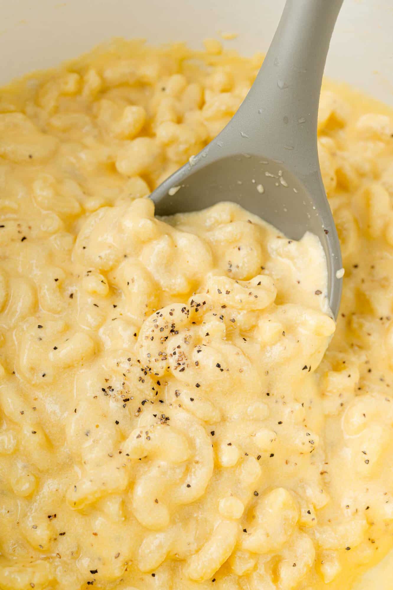 Large serving spoon in a pot of macaroni and cheese.