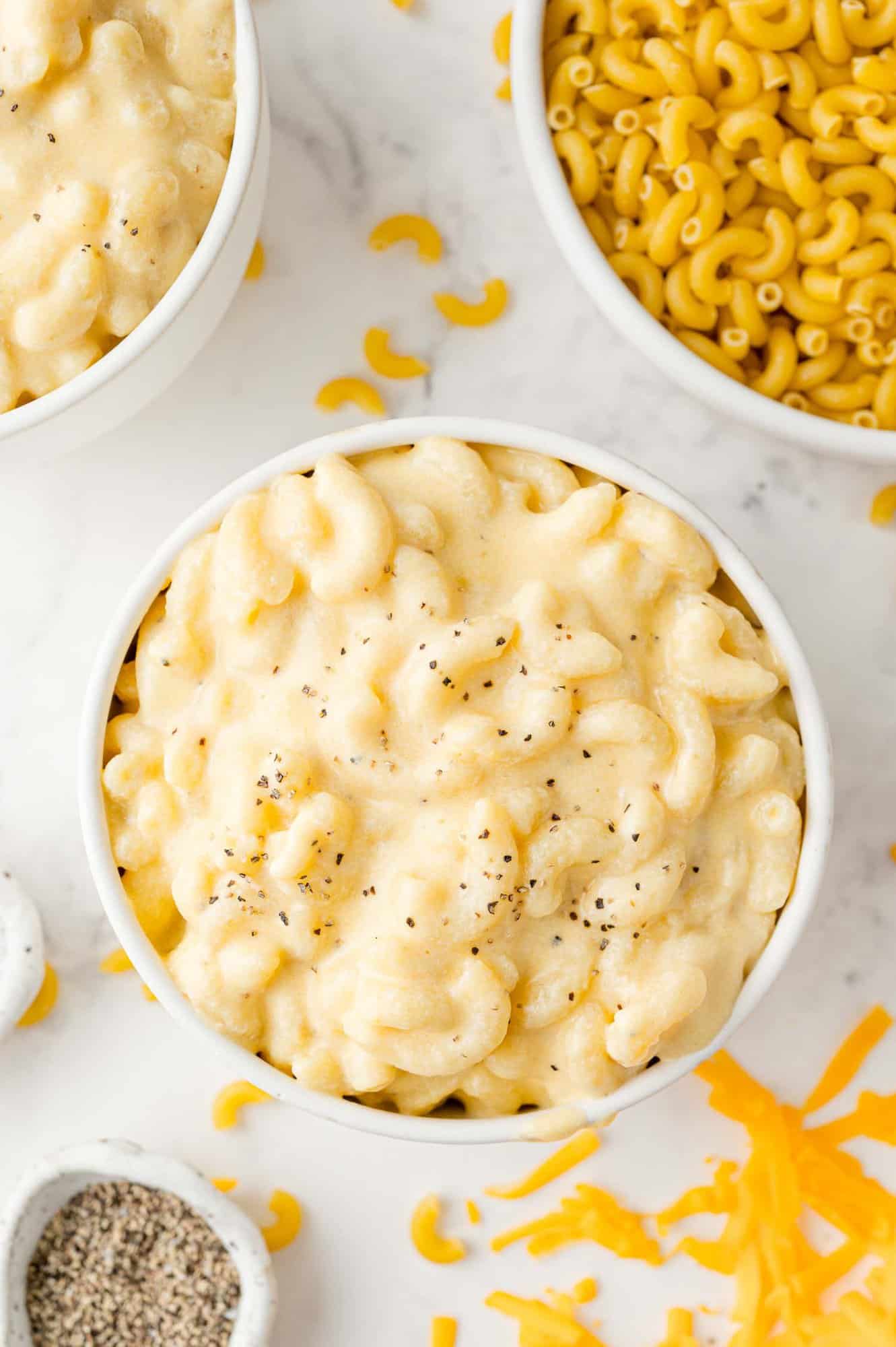 Creamy stovetop mac and cheese in a white bowl, uncooked pasta in the corner of the photo.