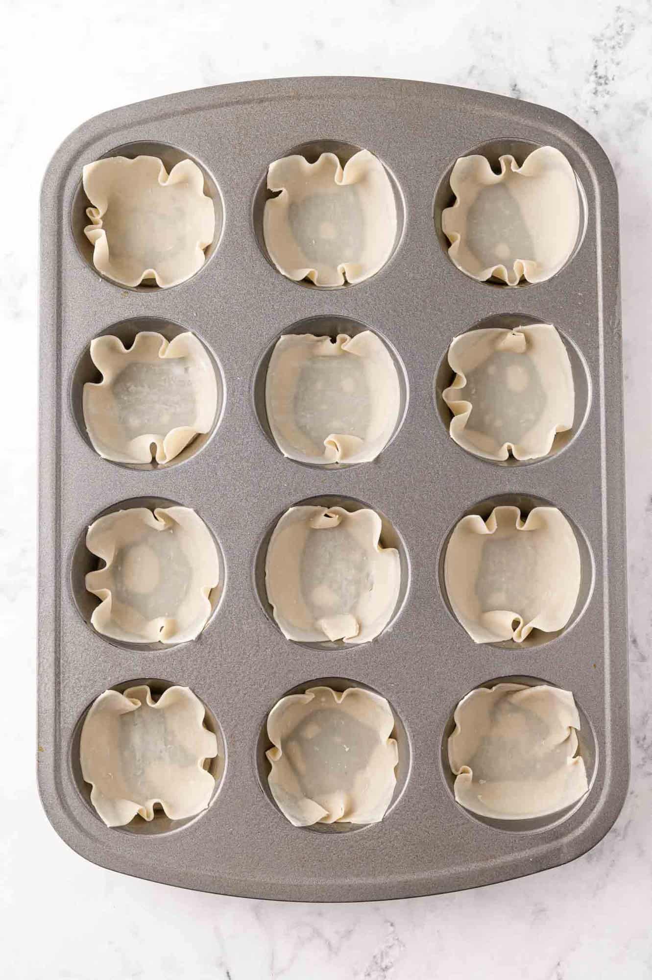 Wonton wrappers pressed into a muffin tin.