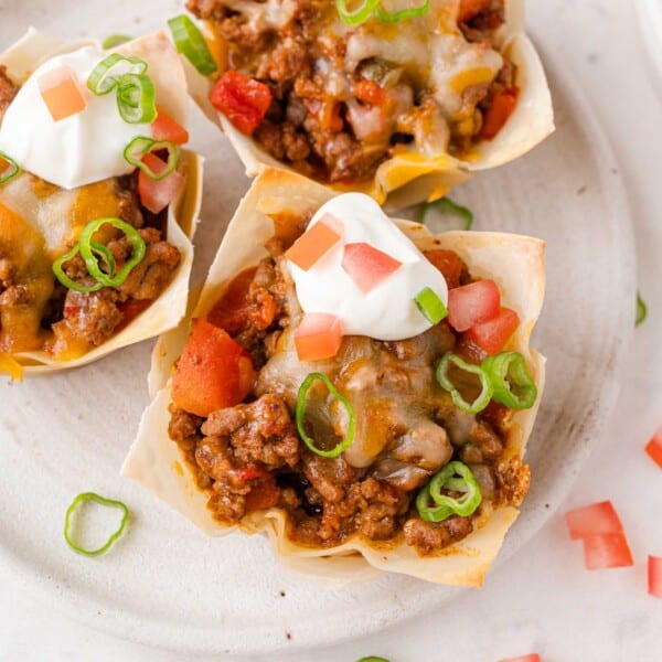 Overhead view of taco cups with sour cream and green onions.