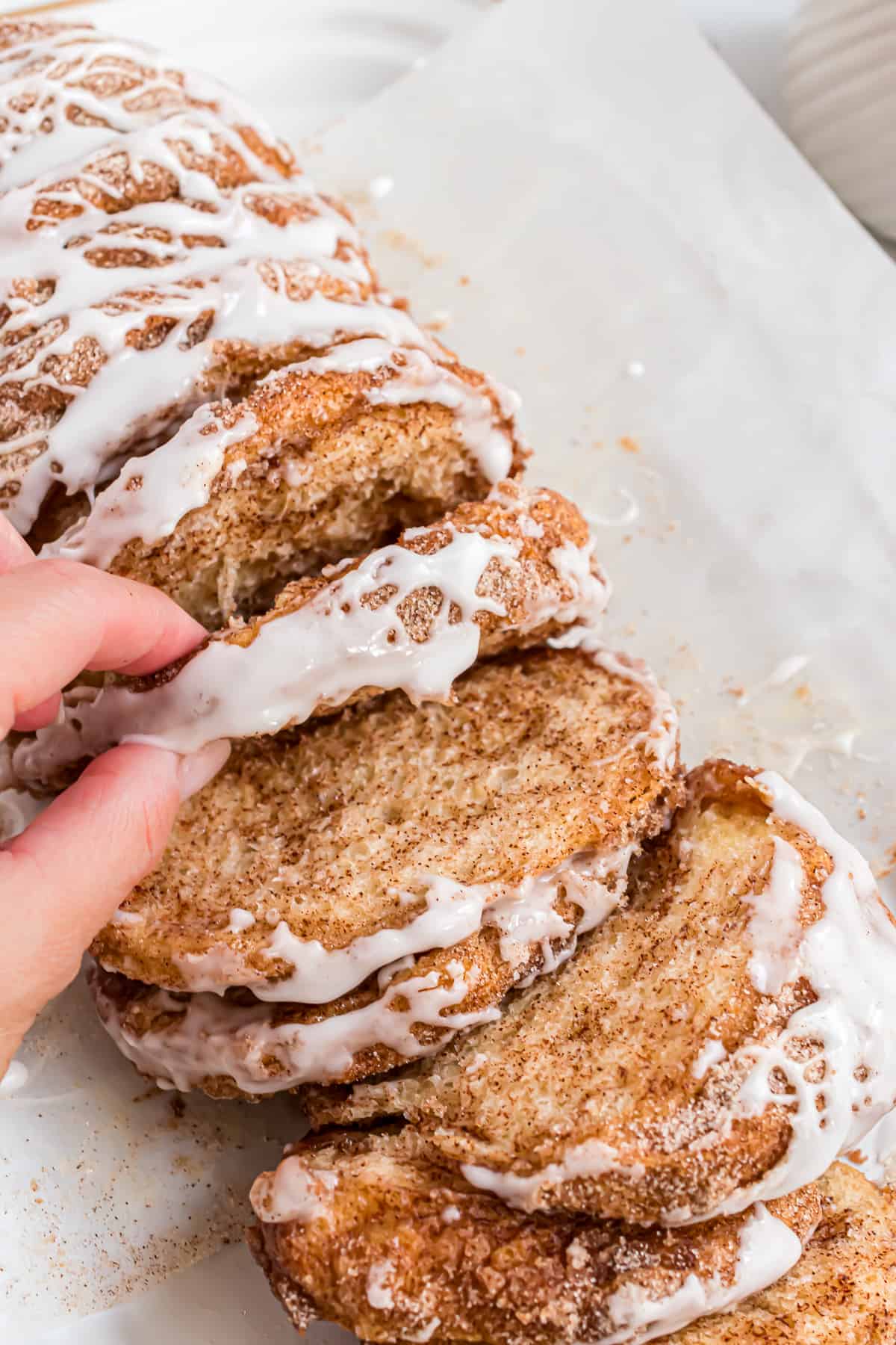 Hand in shot, pulling off a piece of cinnamon sugar pull apart bread.