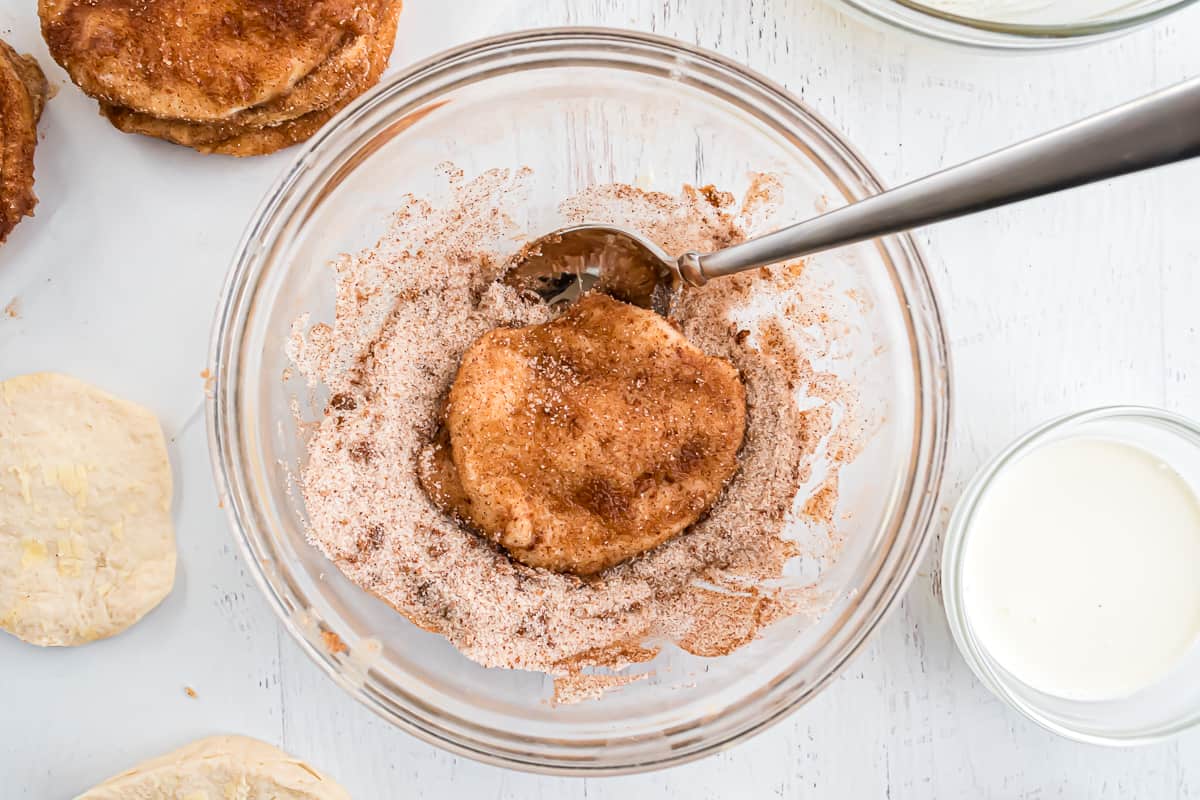 Biscuit being coated in cinnamon sugar mixture.