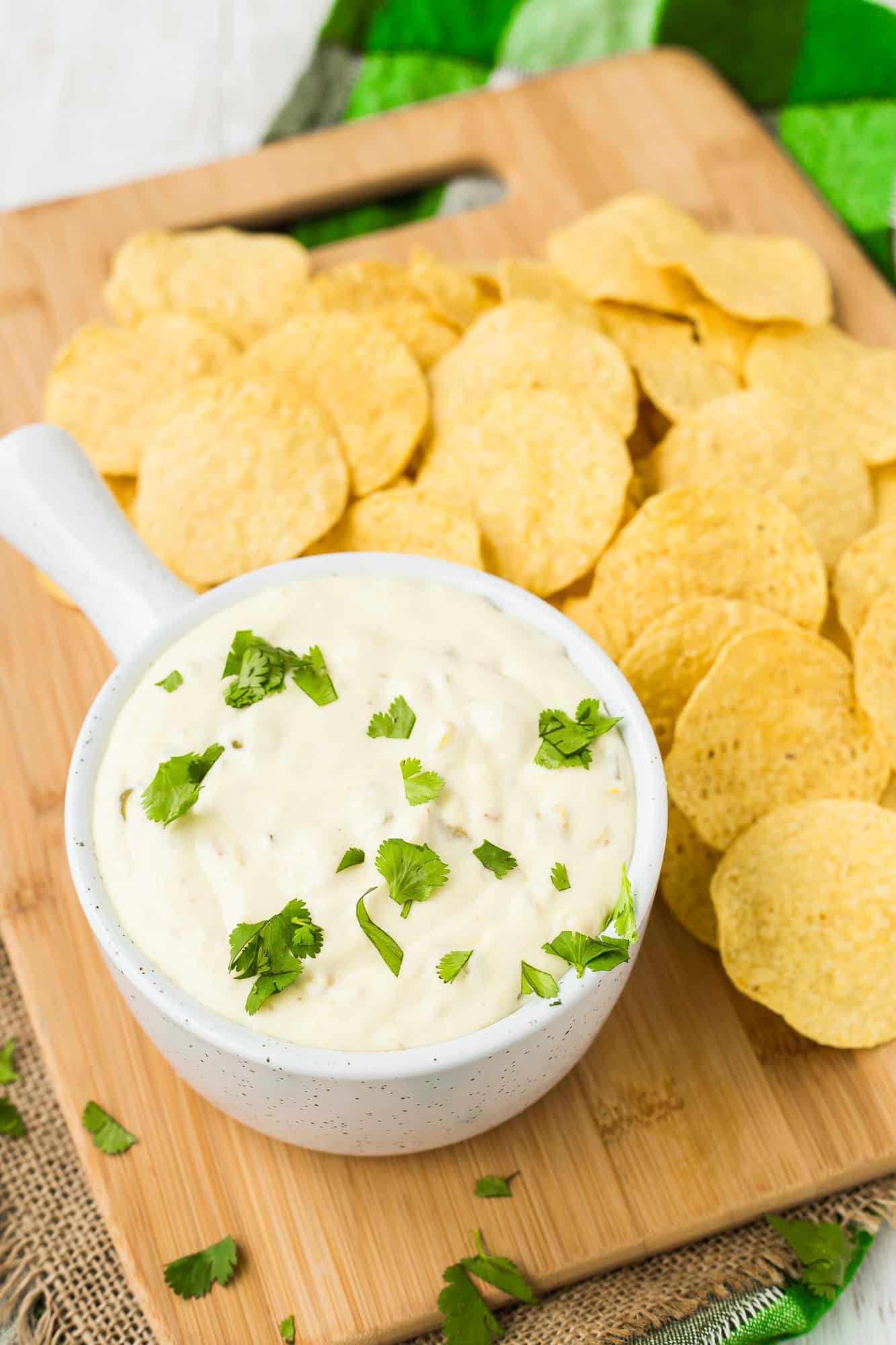 Crockpot queso blanco in a small white bowl, surrounded by chips.