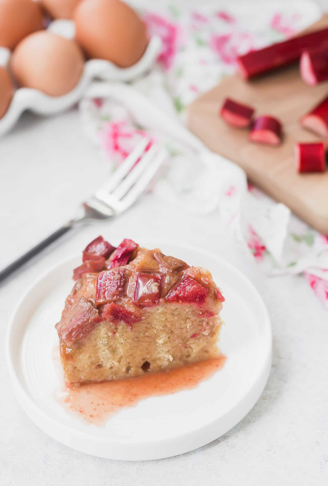 Slice of rhubarb instant pot cake, with rhubarb in the background.