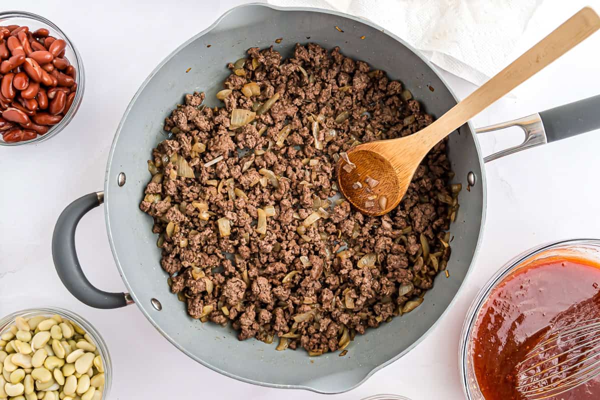 Onions and beef browning in a frying pan.