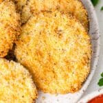 Rounds of crispy air fryer eggplant on a white plate.