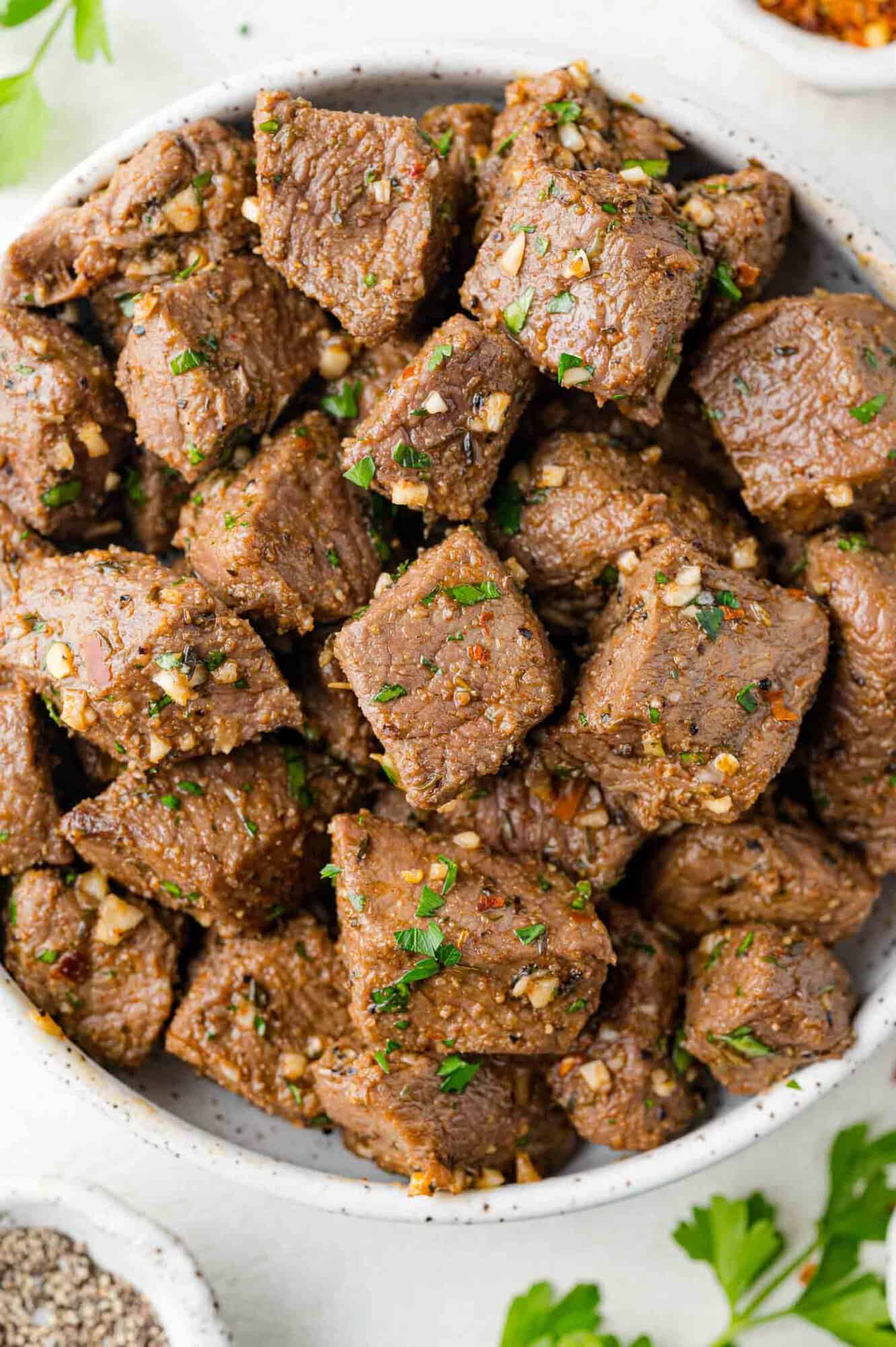 Bowl of air fryer steak bites with garlic and parsley.