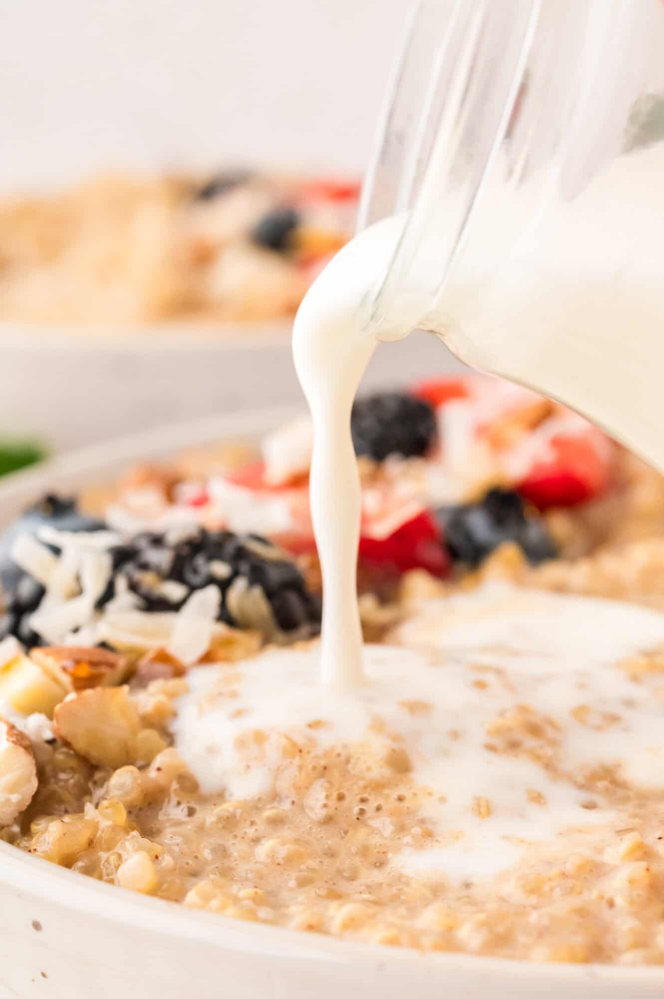 Milk being added to cooked quinoa in a bowl.