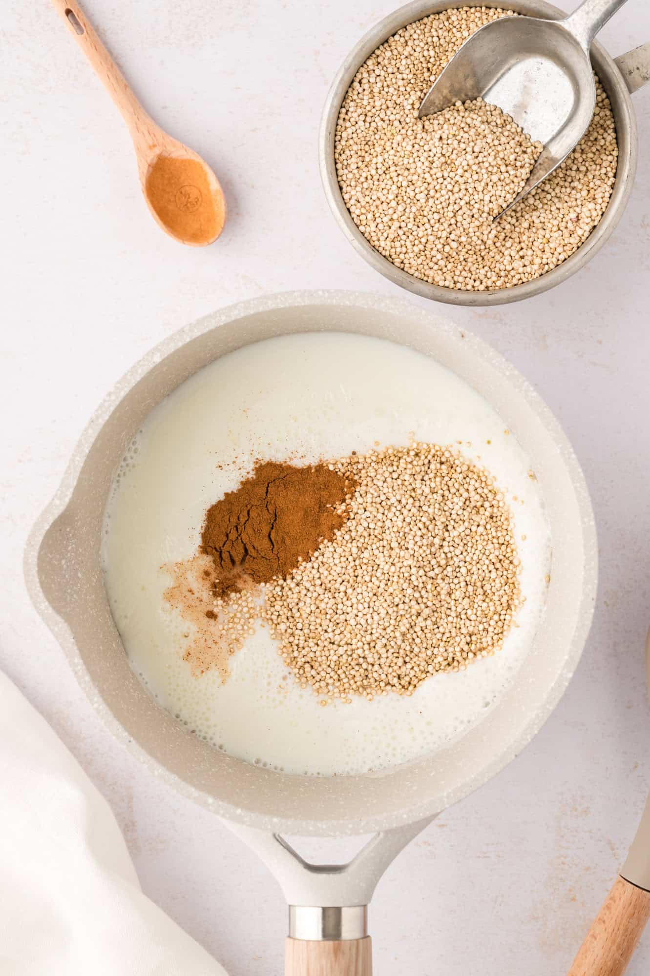 Quinoa and seasonings added to saucepan.