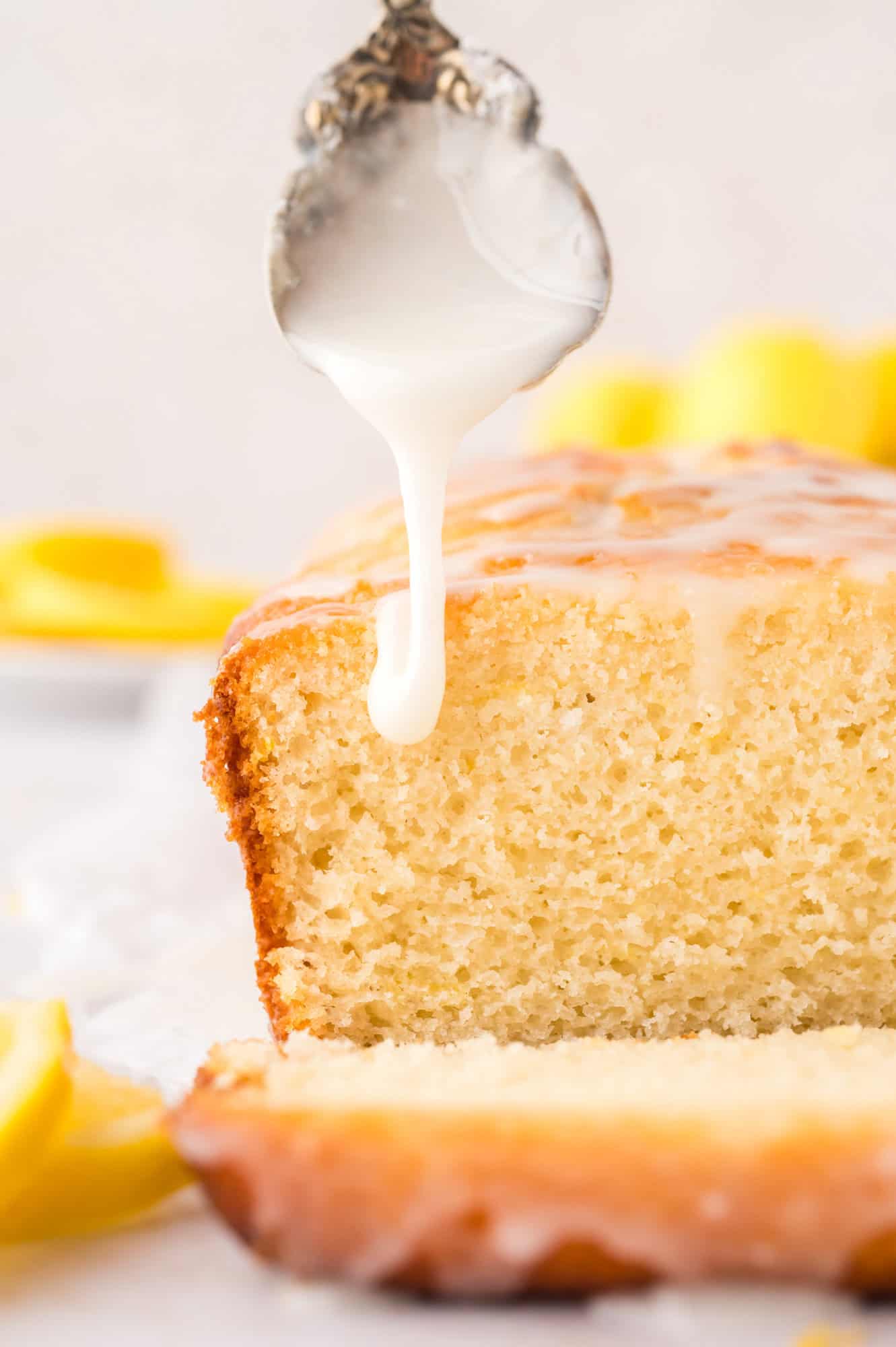 Glaze being drizzled on a cut loaf of lemon bread.
