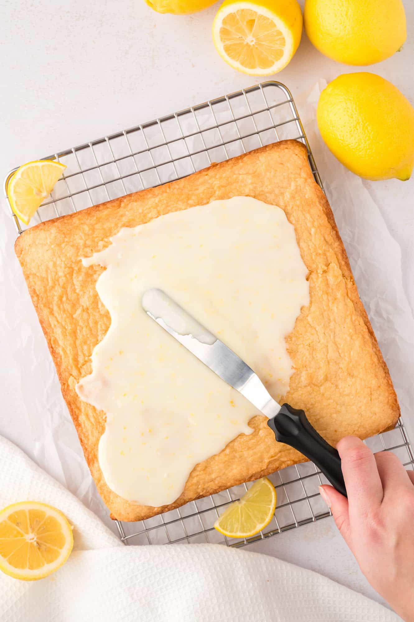 Glaze being spread on lemon brownies.