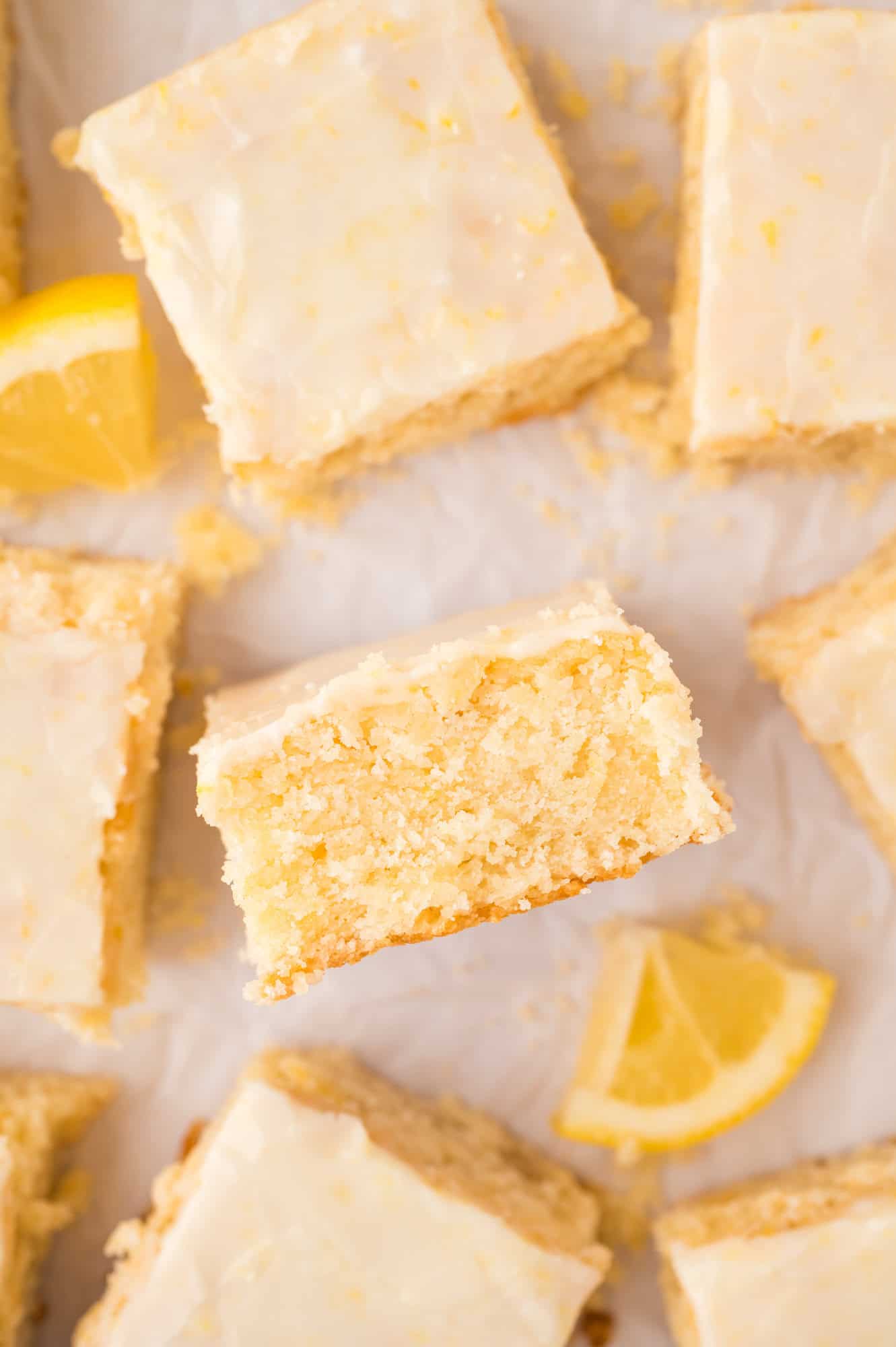 Lemon brownies laid flat on white surface, one turned on its side to show texture.