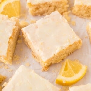 Lemon brownies with glaze, cut into squares on parchment paper.