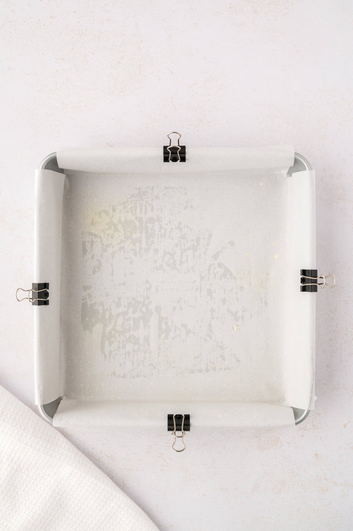 Parchment paper added to baking dish, secured with clips.