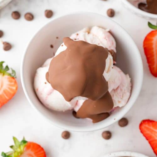 Overhead view of magic shell on top of strawberry ice cream, strawberries scattered around.