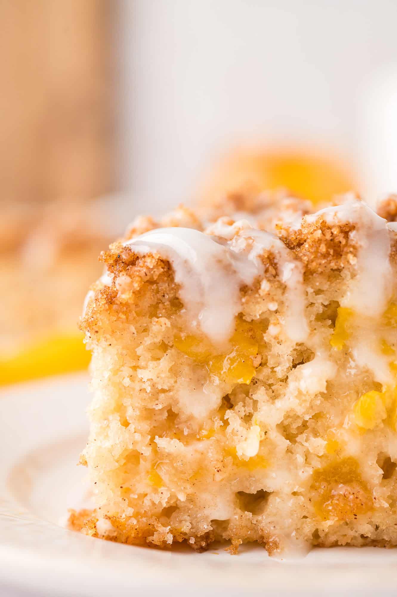 Close up of a slice of peach coffee cake with streusel and glaze.