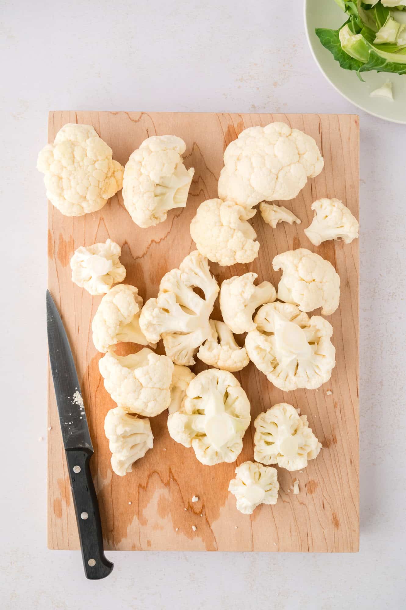 Cauliflower being cut on a cutting board.