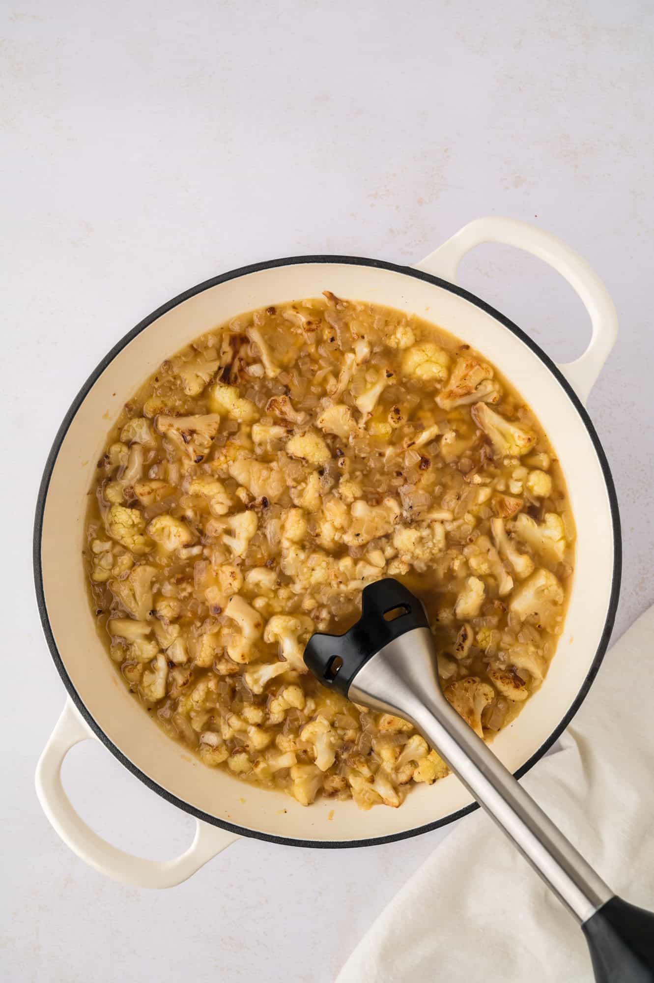 Soup being pureed with an immersion blender.