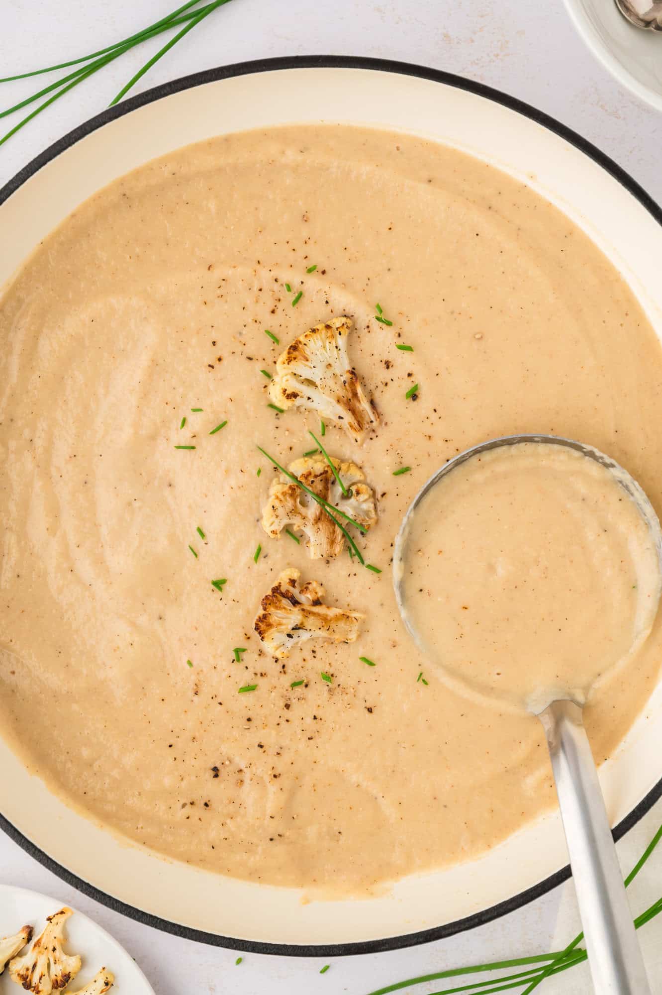 Cauliflower soup in a large pot with a ladle.