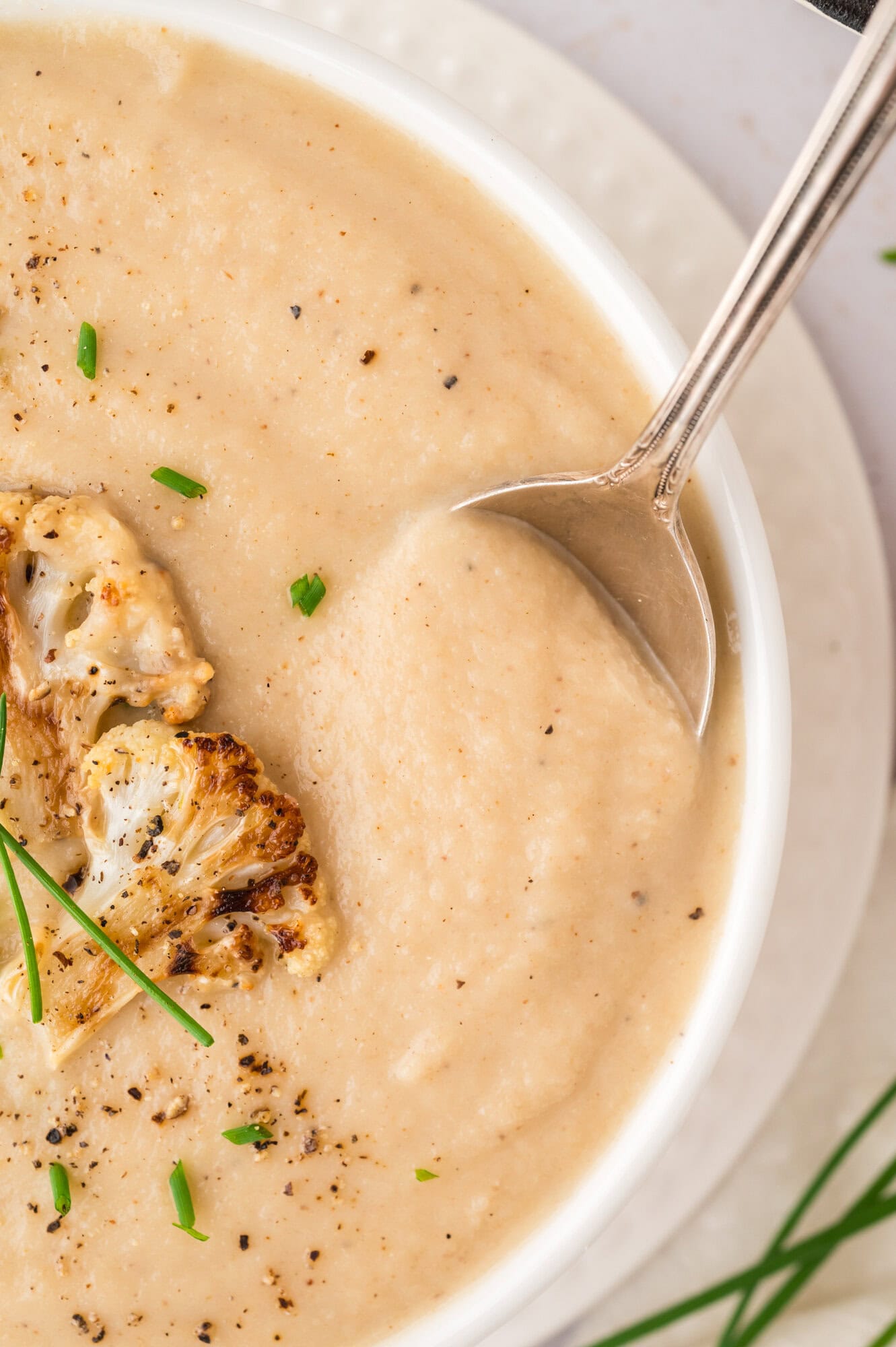 Cauliflower soup on spoon, showing texture of soup.