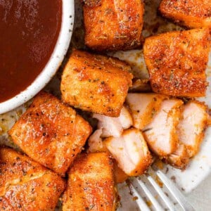 Air fryer salmon bites on a plate, one flaked open to show texture.