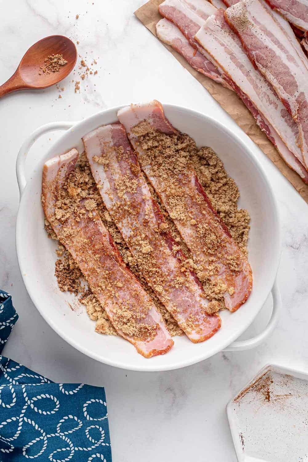 Bacon being dipped in sugar and spice mixture.