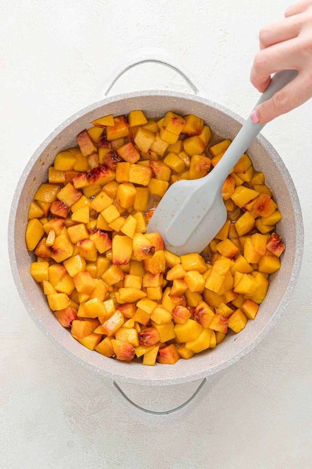 Start of peach sauce, in a sauce pan, being stirred.