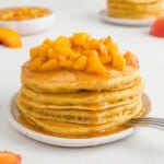 Stack of peach pancakes topped with peach sauce.
