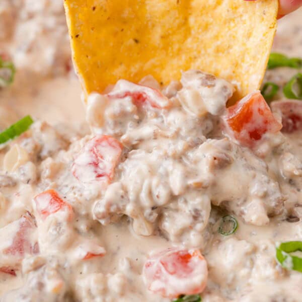 Sausage dip being scooped up with a tortilla chip.