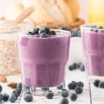 Blueberry smoothie in a short glass, topped with fresh blueberries.