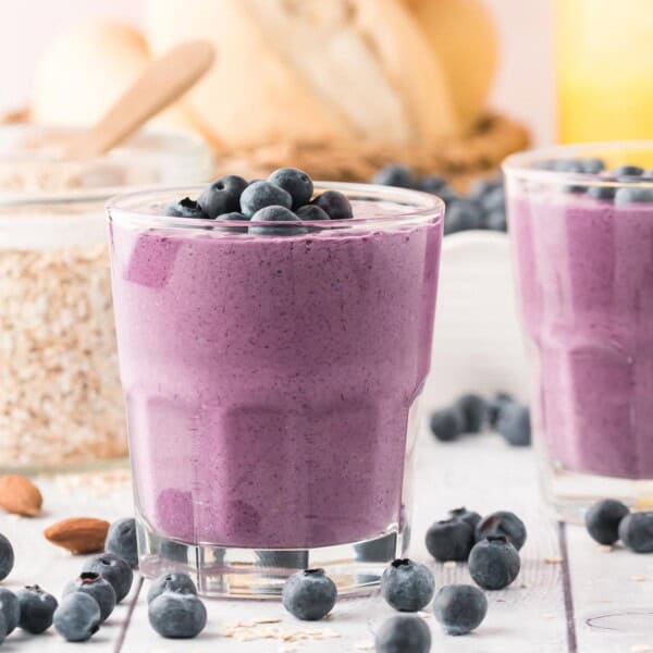 Blueberry smoothie in a short glass, topped with fresh blueberries.