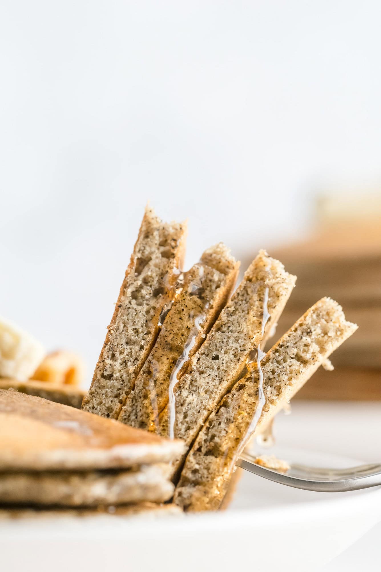 Wedges of buckwheat pancakes on a fork, drizzled with syrup.