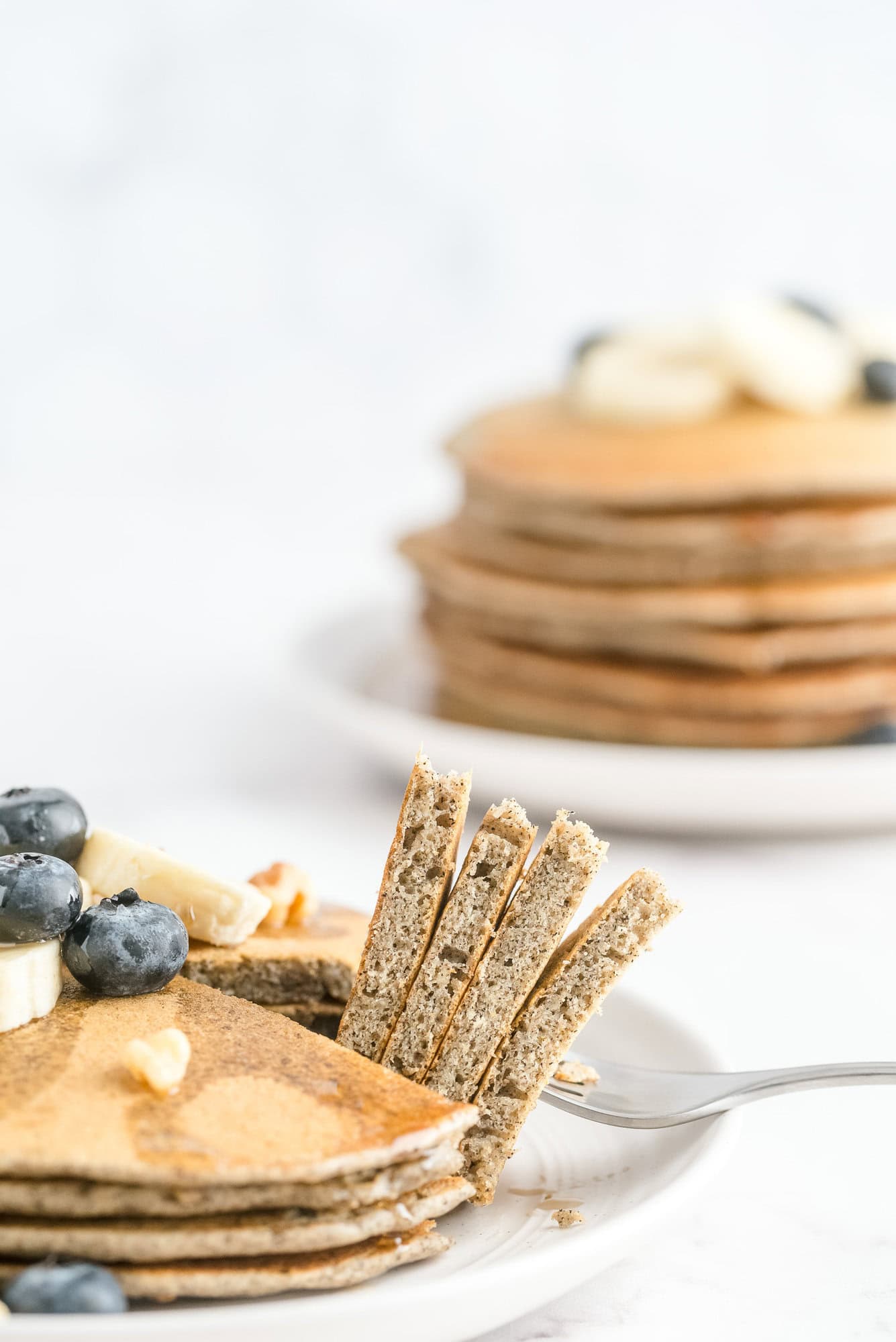 Buckwheat pancakes, two stacks, one partially cut and on a fork.