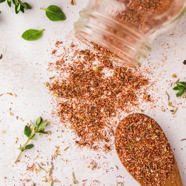 Blackening seasoning spilling out of a jar, and on a spoon.