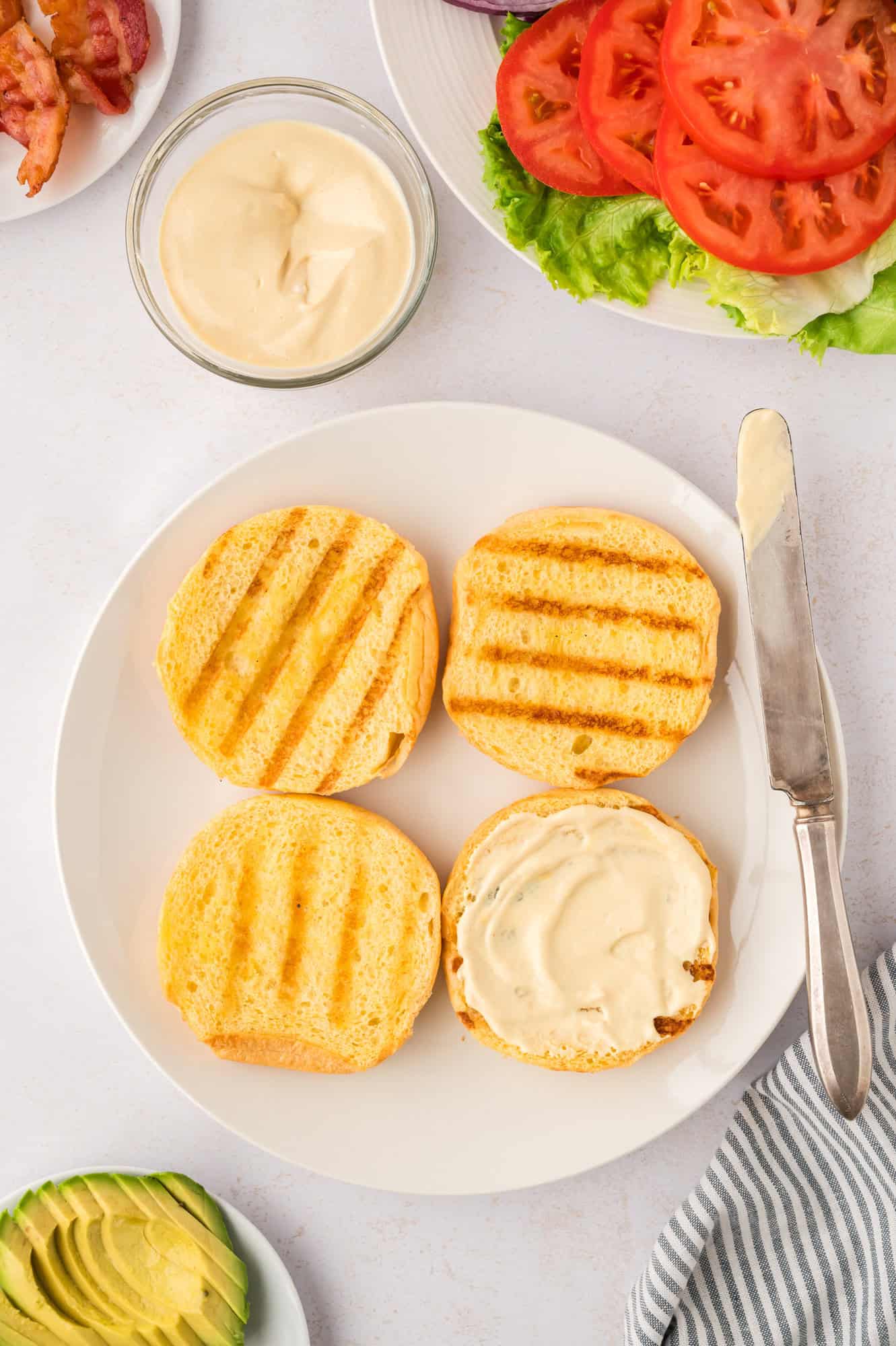 Toasted buns, one with sauce spread on it.