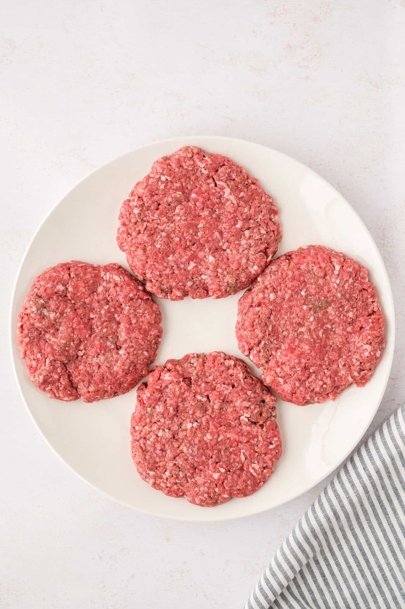 Four uncooked burger patties.