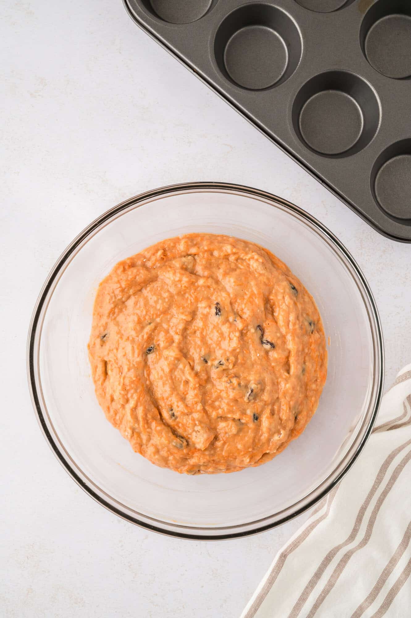 Completed muffin batter, in clear glass mixing bowl.