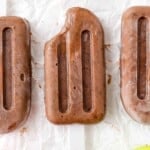 Three chocolate pudding pops, one with a bite removed.